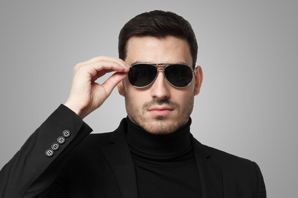 Close up shot of bodyguard or secret agent wearing suit and sunglasses, isolated on grey background