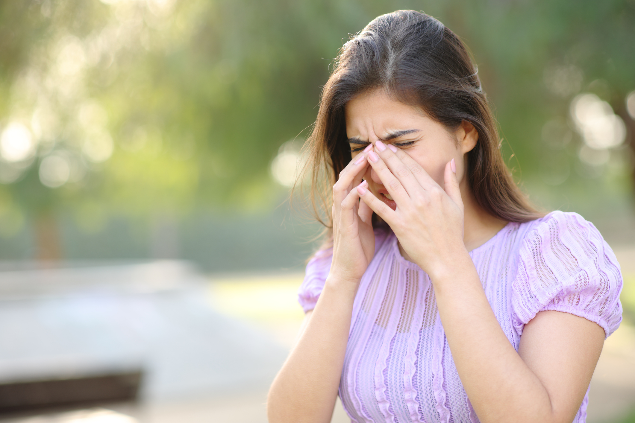 Allergic woman scratching eyes in a park, itchy eyes due to allergies
